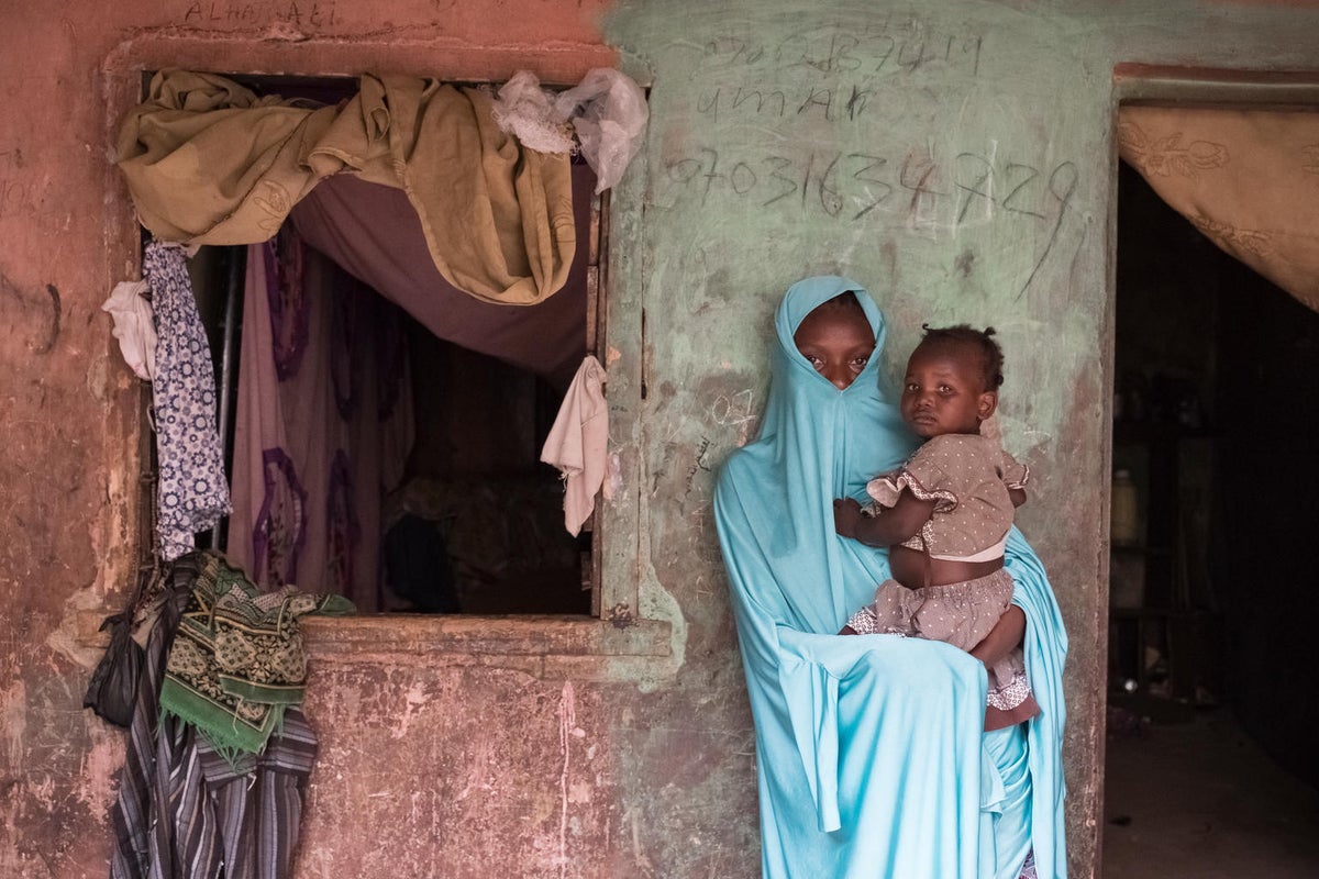 A woman wearing a burqa is holding a baby girl.