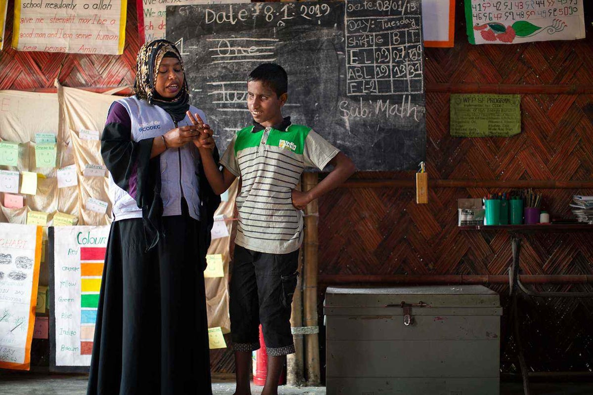 Twelve-year-old Motalab, who is blind, stands in front of his fellow students and helps teacher Shahin Jannat during an English lesson at the CODEC/UNICEF Learning Centre