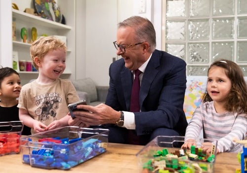 Prime Minister Anthony Albanese sitting and laughing with young children. 