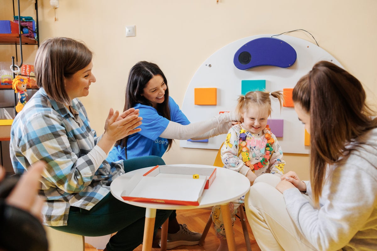 A woman watching a young girl participating in occupational therapy.