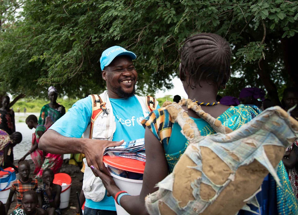 UNICEF Emergency Specialist Joseph Adiomo hands a water kit to a woman affected by the flooding.