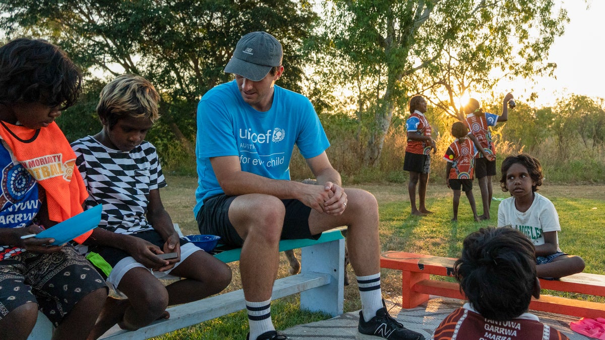 A group of children and a young man sitting on a bench.