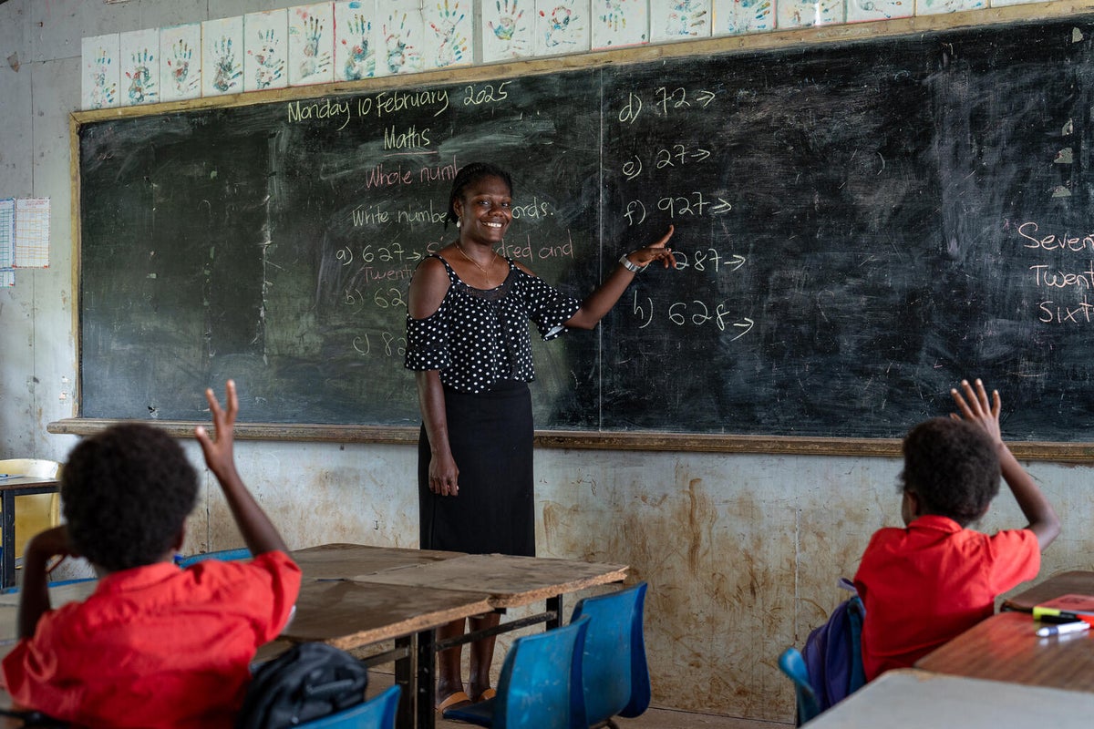 A teacher continue lessons with students in her classroom.