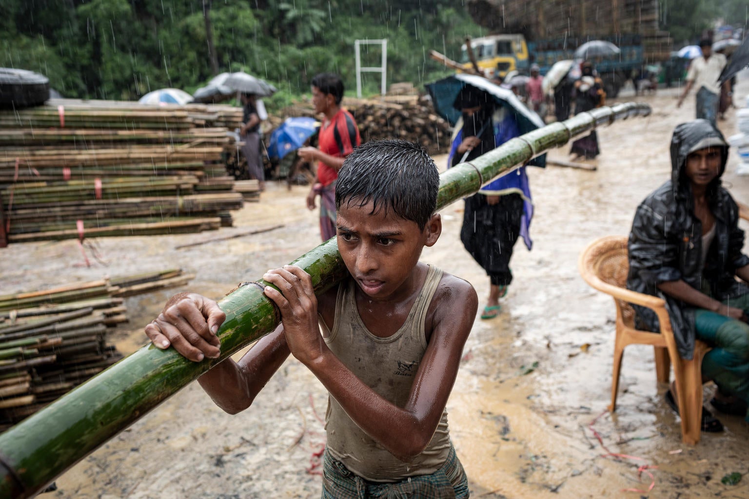 Cox's Bazar in Bangladesh, a boy carries a bamboo pole, used for building basic shelters, were unloaded near the settlement.