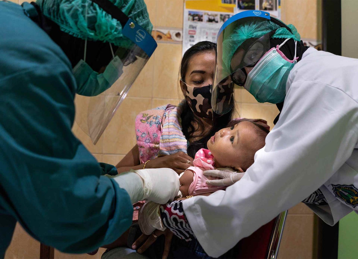 Health workers vaccinate a child