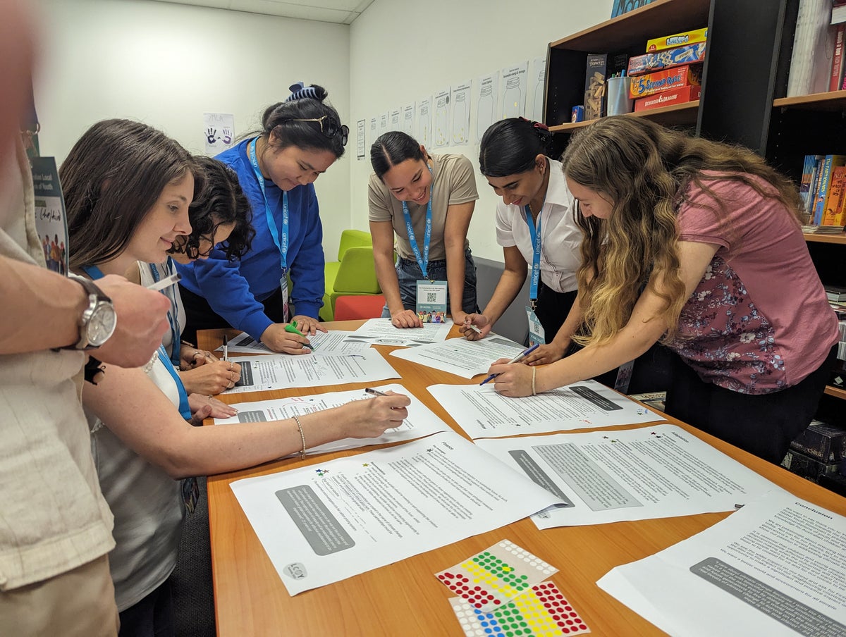 A group of young people sitting at a table looking at documents