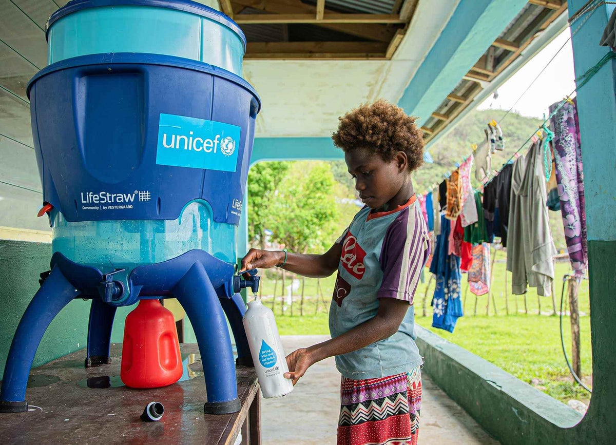 Seraphine, 9, filling up her UNICEF-provided water bottle from the Lifestraw water filter that was set up at her school