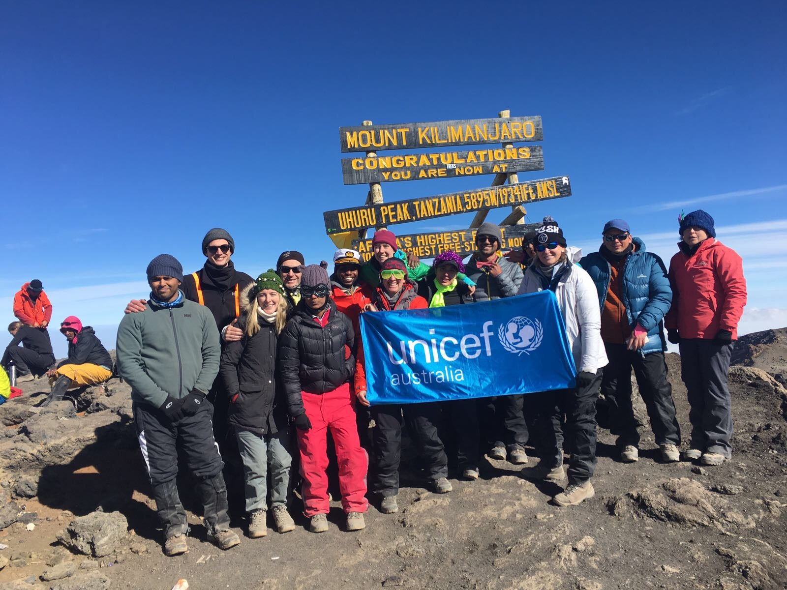 A group of people at the top of Mt. Kilimanjaro. They are holding a UNICEF flag.
