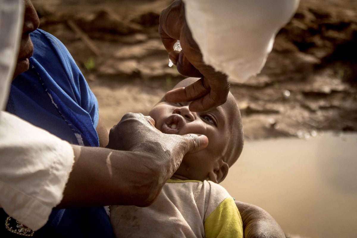 The vaccinator Adama Traore vaccinating Hachime, 11 months, with his first dose of vaccine. Hachime lives with his parents on the gold panning site of Massakama and had never been vaccinated before. 