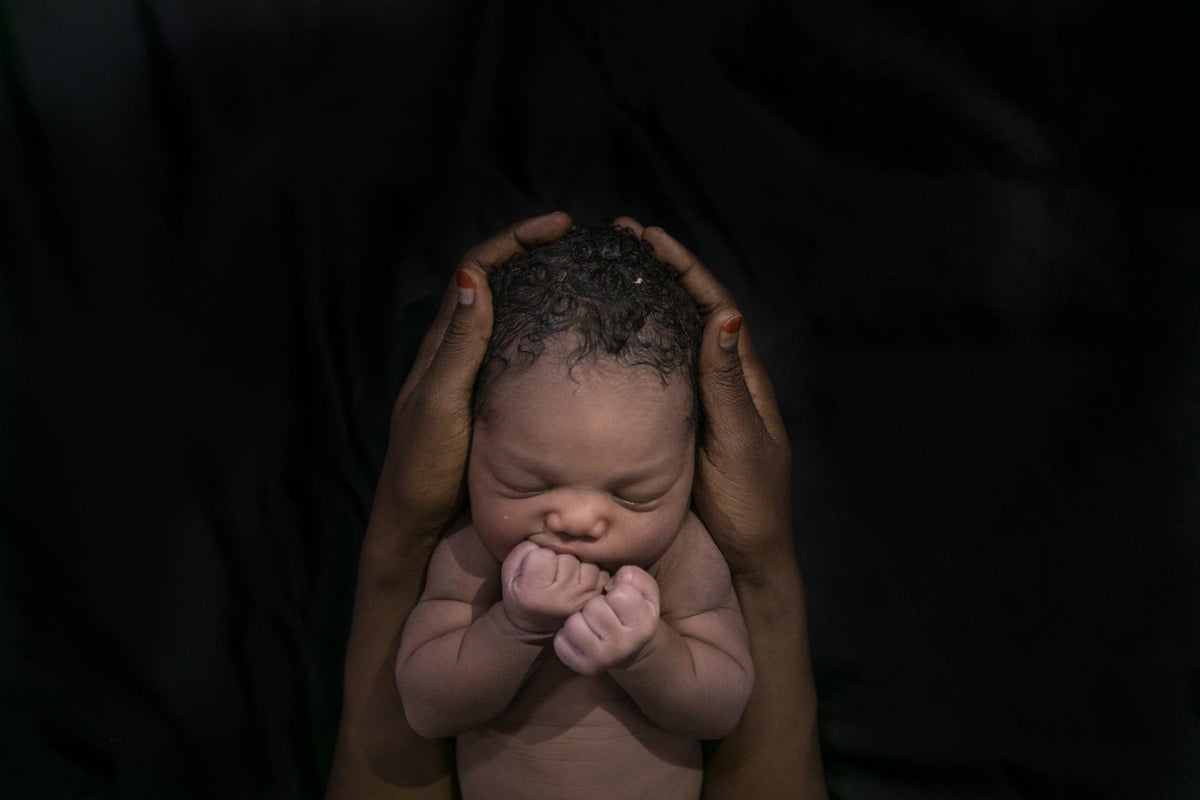 A newborn baby held by two hands.