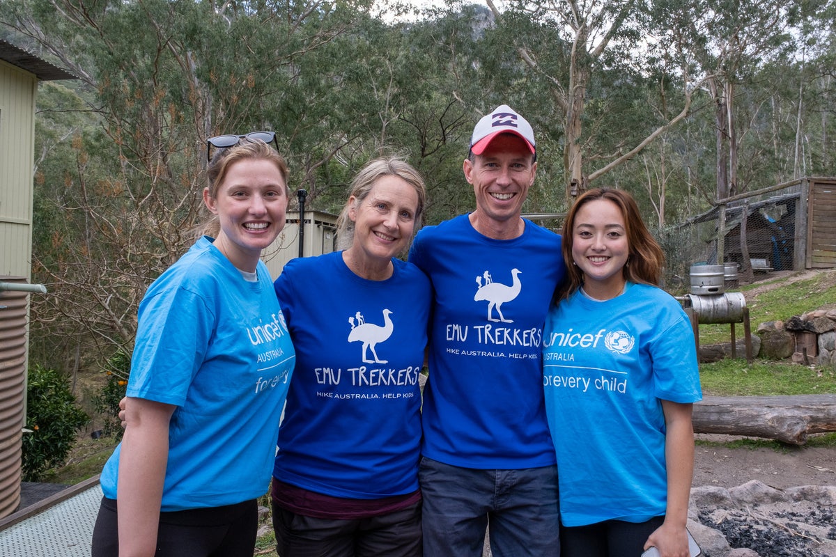 A male and female wearing Emu Trekkers shirts standing with two female UNICEF Australia employees. 