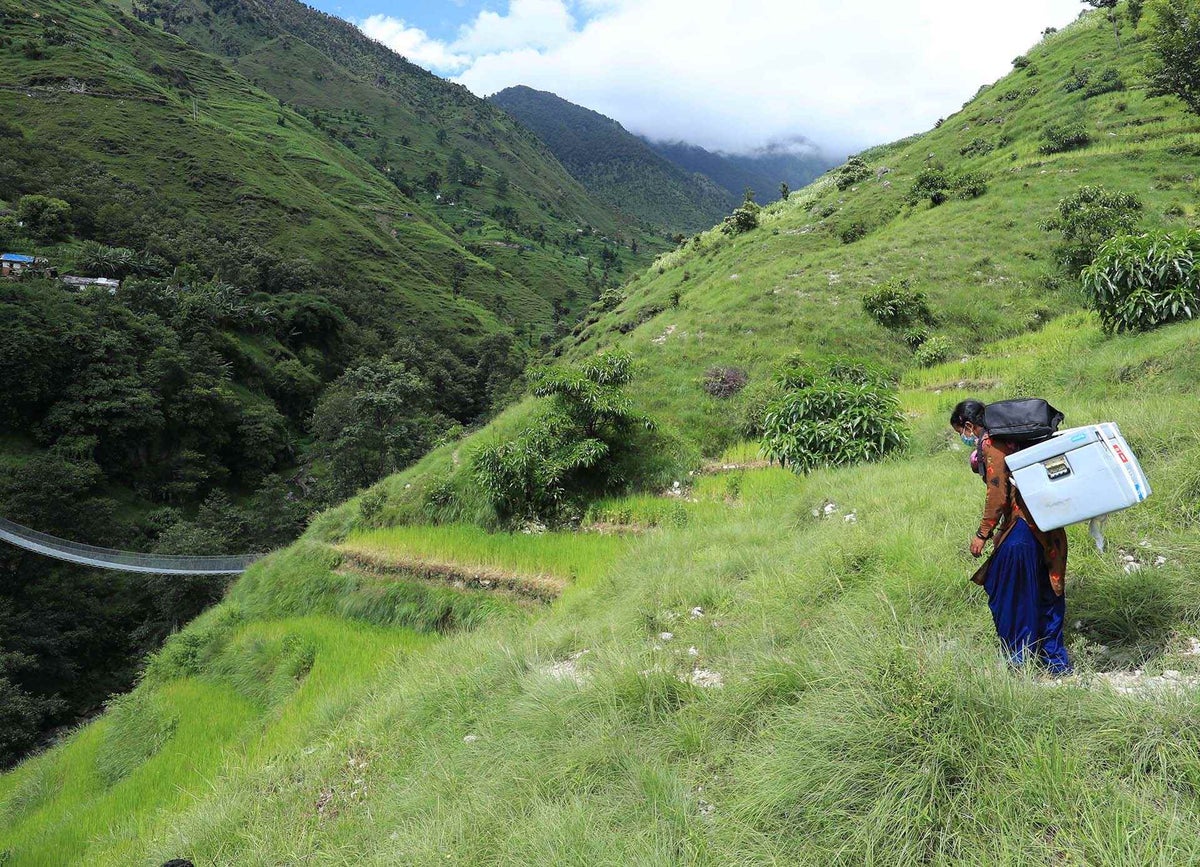 Birma carries COVID-19 vaccines to a health post where she works as a support staff. 