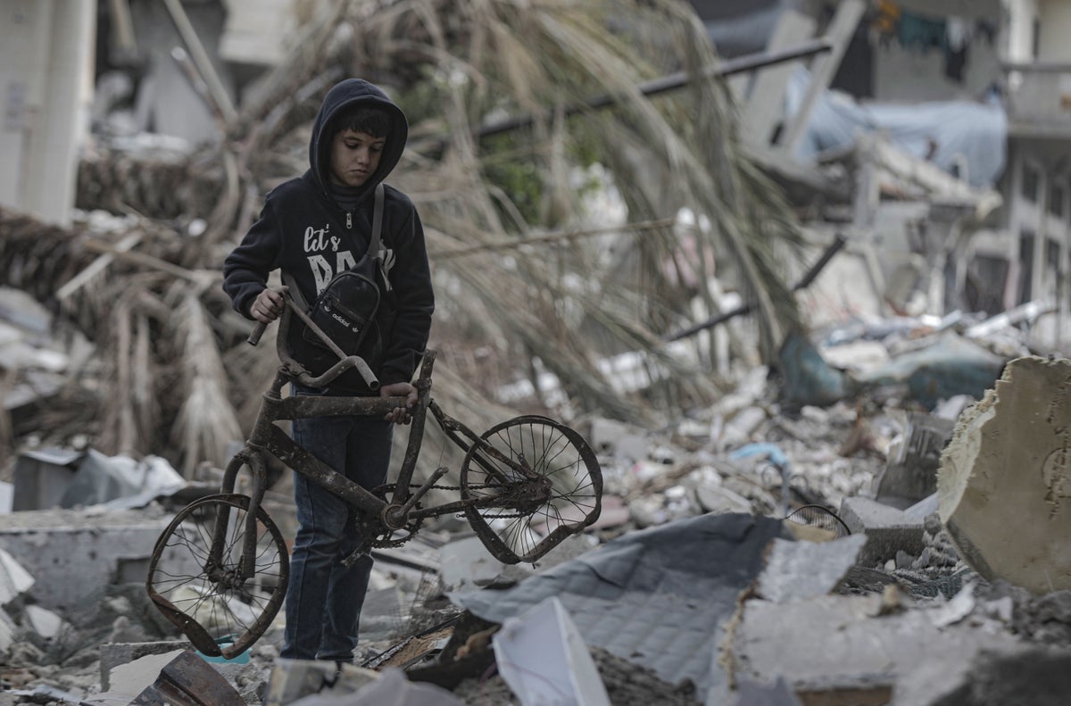 A 10-year-old boy holds a destroyed bicycle as he searches through the rubble of his home in Gaza.