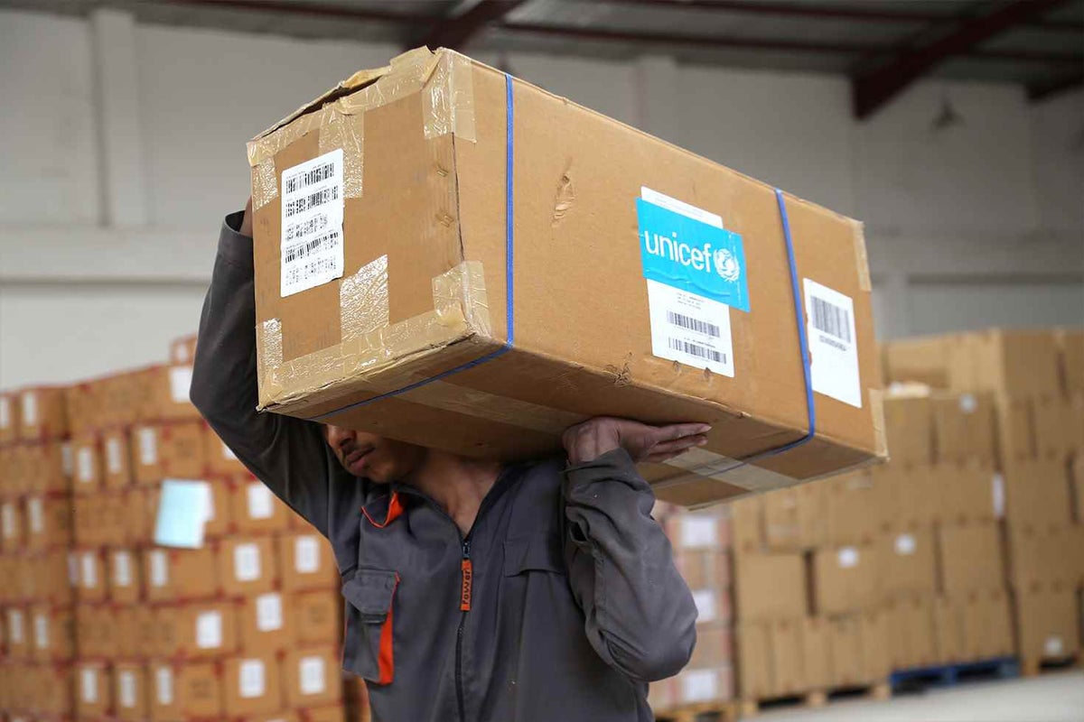A UNICEF staff member carries a box of supplies