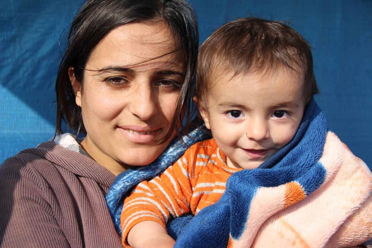 Metab carries her one year-old son Khalil in her arms at the Domiz refugee camp in 2014.