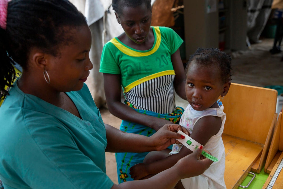 A toddler is being assessed for malnutrition by a health worker.