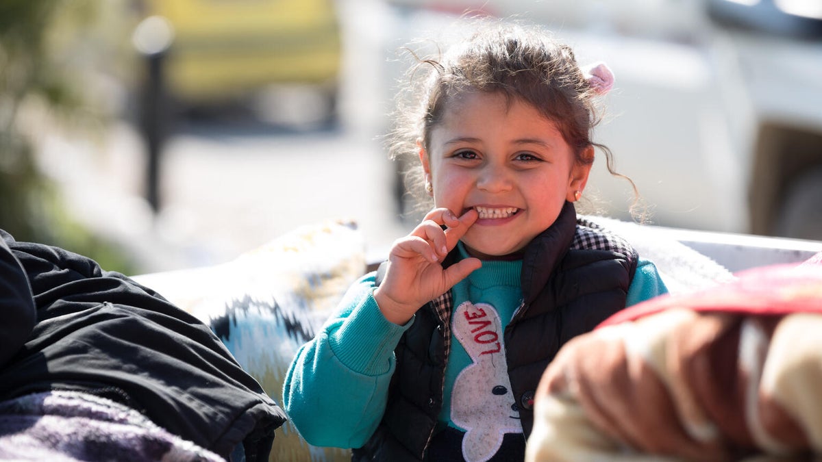 A young Syrian girl displaced from the earthquakes sits in her car