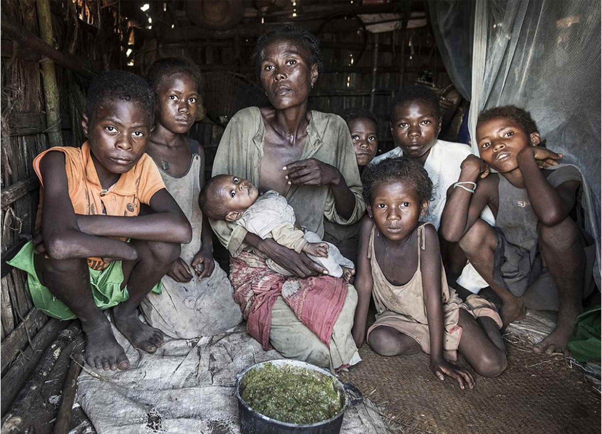 Vola breastfeeds Mosa while her other children eat cooked cassava leaves – the family's only meal of the day.
