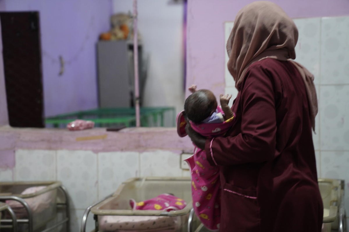 At a support centre, a carer attends to one of the youngest children who's waiting to be adopted.