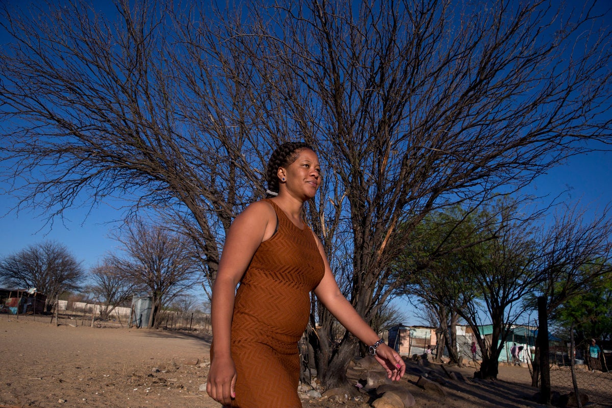 Livey walks on a dirt road. There's a big tree behind her.