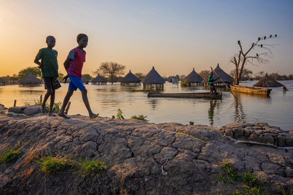 children walking along a dyke in their community after floods