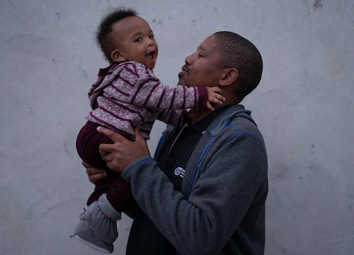 Eight-month-old Khuma squeals with delight as his father, Bongani, picks him up in South Africa.