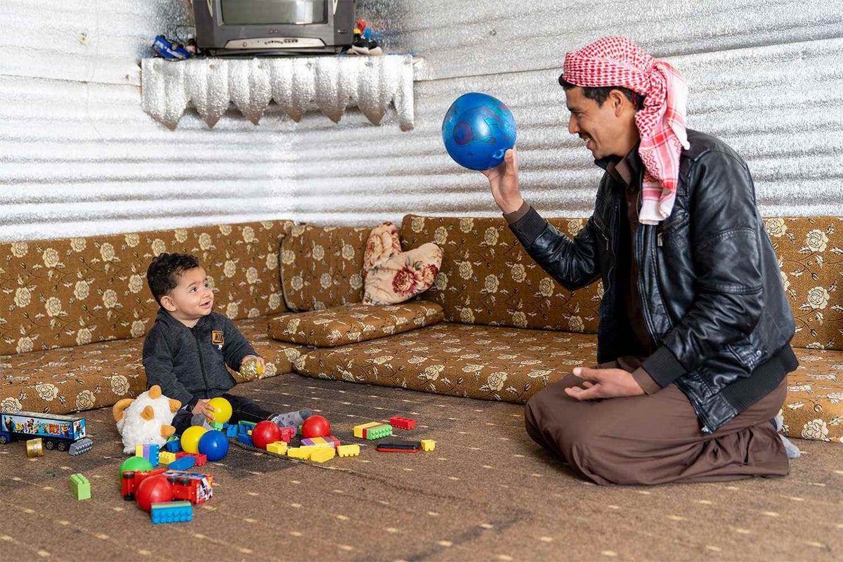 Father plays with baby in refugee camp.