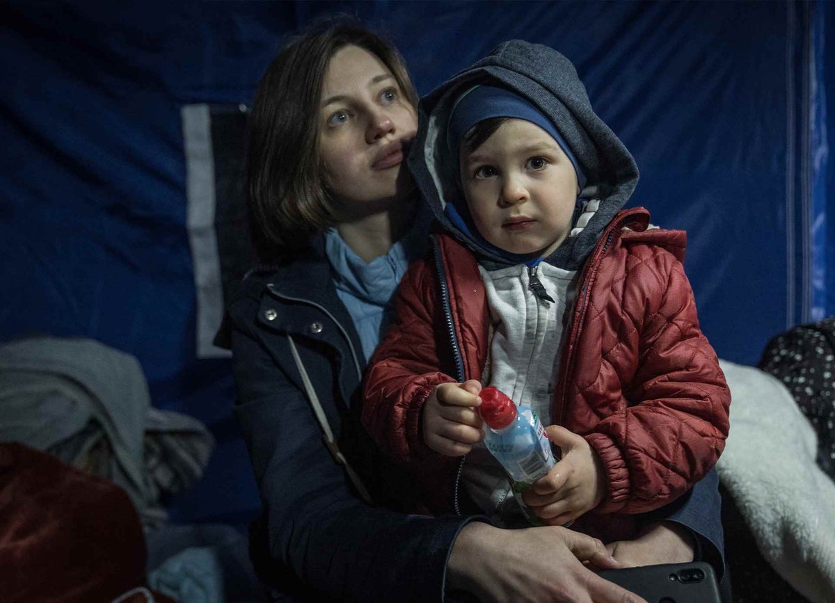 Mother sits with child in tent