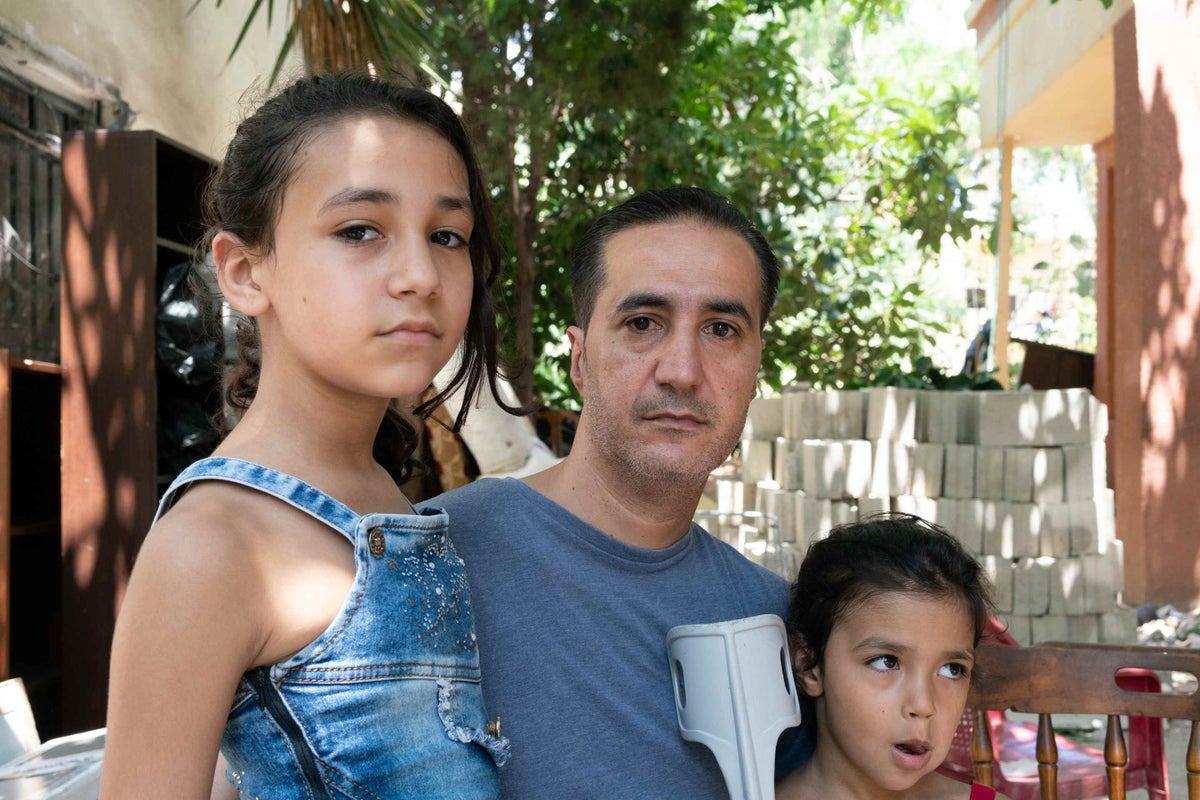 Ahmad with his daughters outside his house, severely damaged by the explosion