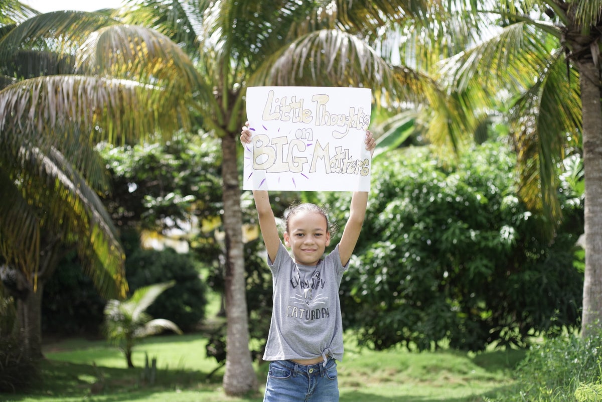 A young girl holding a sign that says "Little Thoughts on Big Matters"
