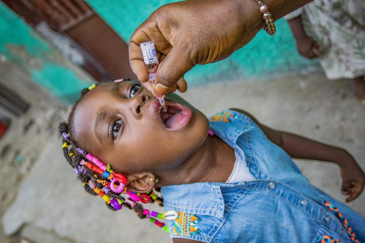 A young girl receives a droplet vaccine.