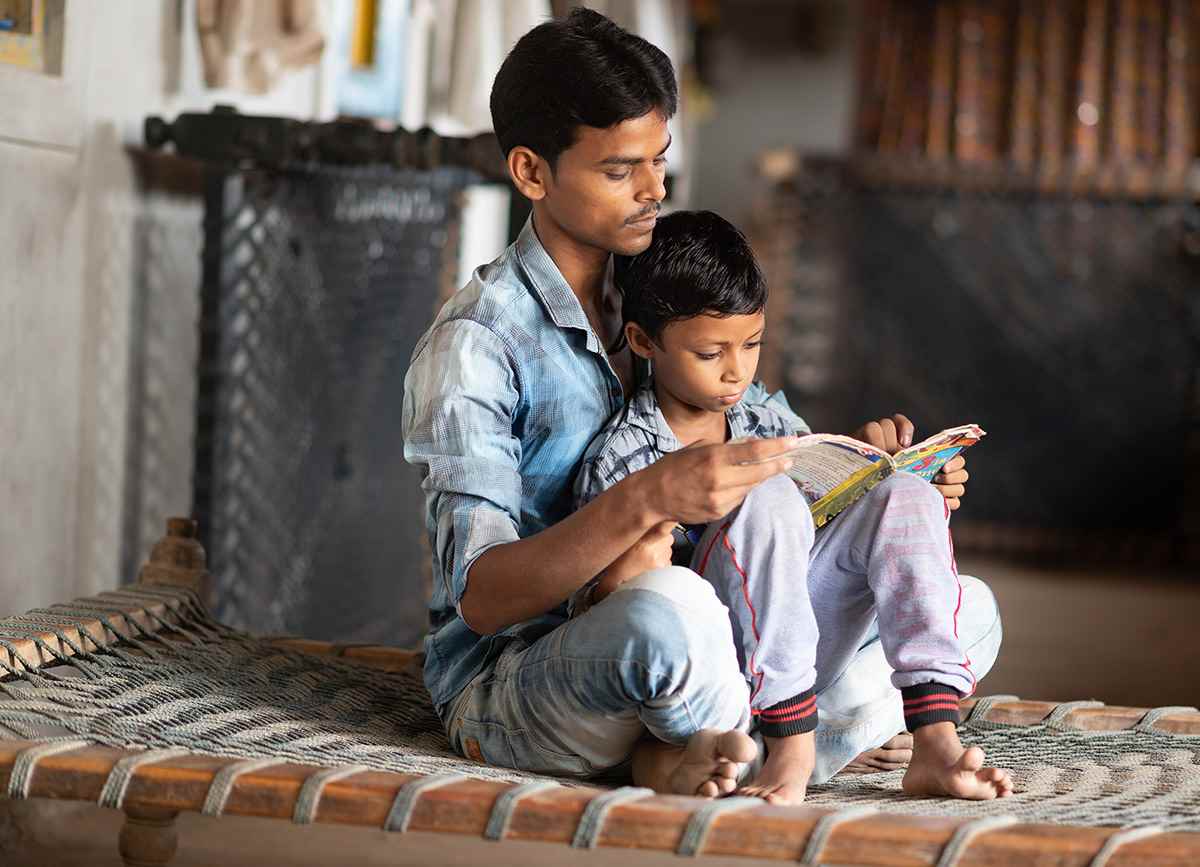 Six-year-old Som sits in his father's lap as they read together.