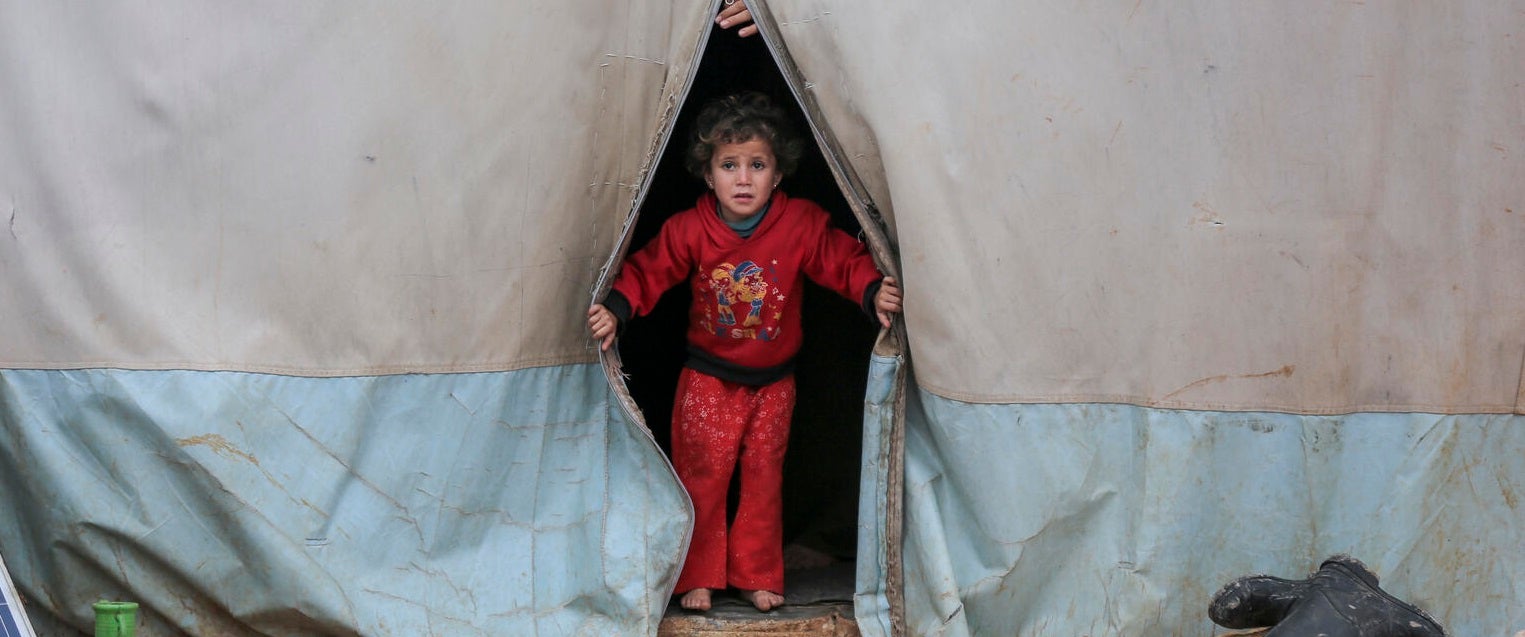  A child looks out a tent in Kafr Losin Camp in northwest Syrian Arab Republic