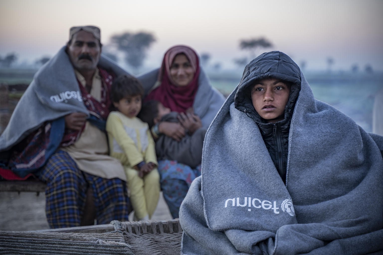 8-year-old Sameer and his family sit on a charpoy outside their house after receiving UNICEF’s winter kit in Pakistan.