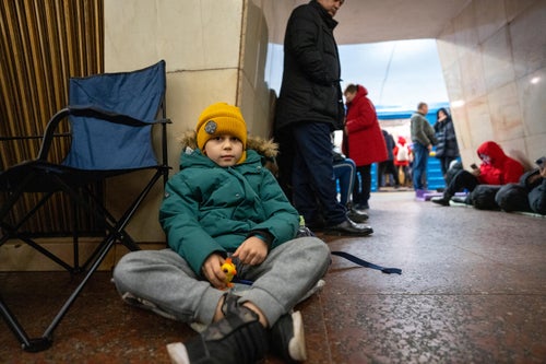 A child wearing winter clothing sits on the floor of a metro station that has been turned into a shelter in Ukraine.