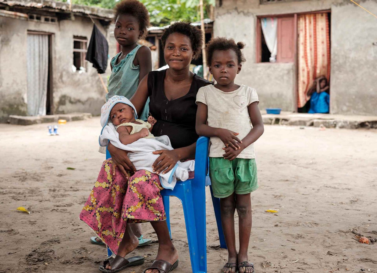 Mother nursing newborn with two children  