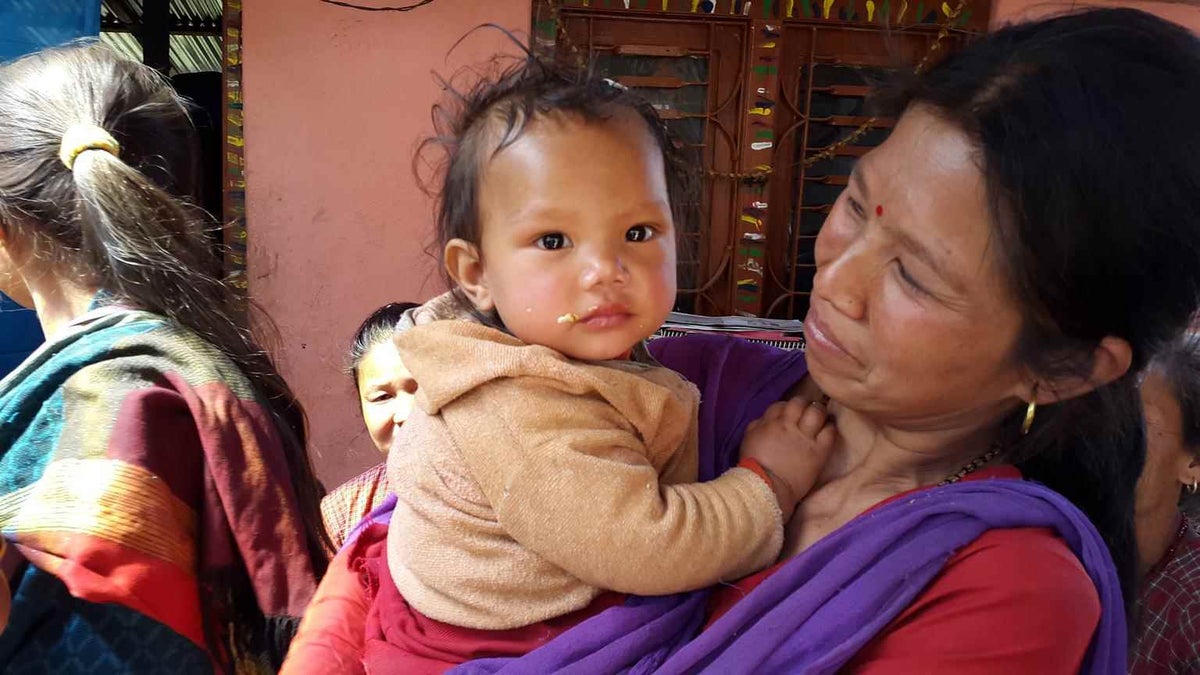 A mother waits for her daughter to receive a measles/rubella vaccine at an emergency vaccination site in Nepal. 