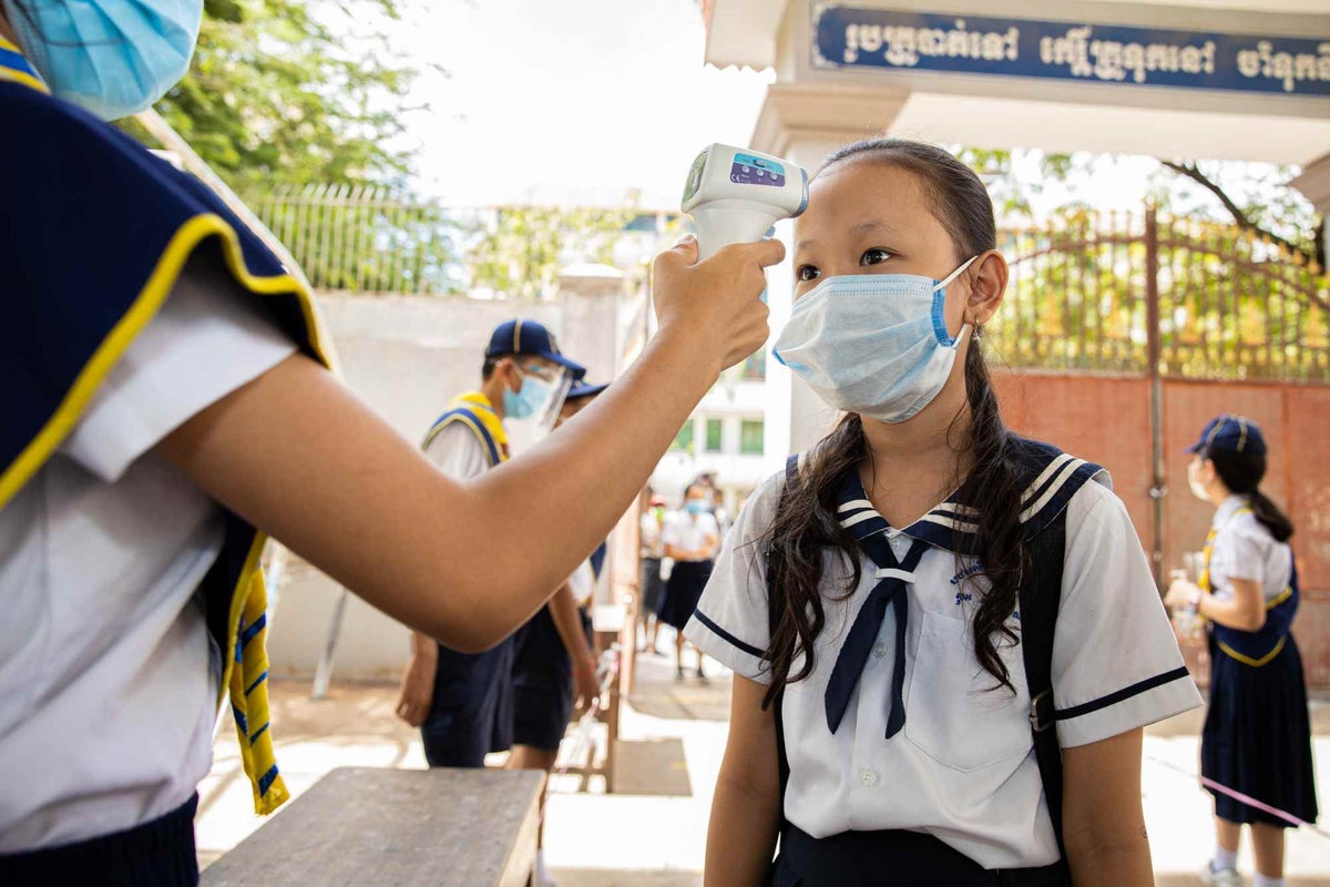 Students provide hand sanitiser and check the temperatures of their classmates before they enter school. 