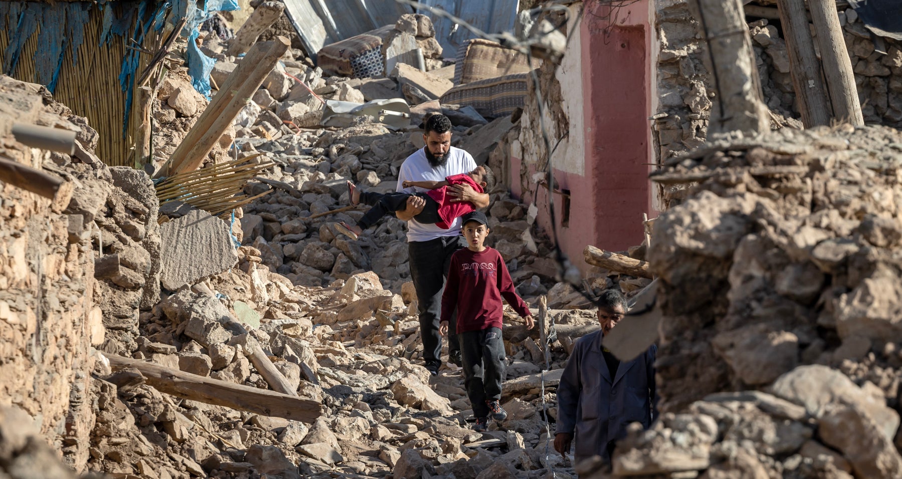 A man walks through the rubble carrying a child after an earthquake hit Morocco on 9 September 2023.