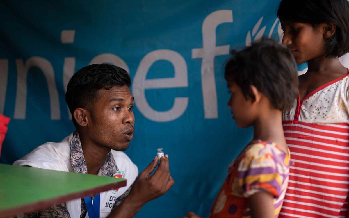 Vaccinator Chutan explains what a cholera vaccine is to two children, at a UNICEF-supported vaccination site back in May 2018.