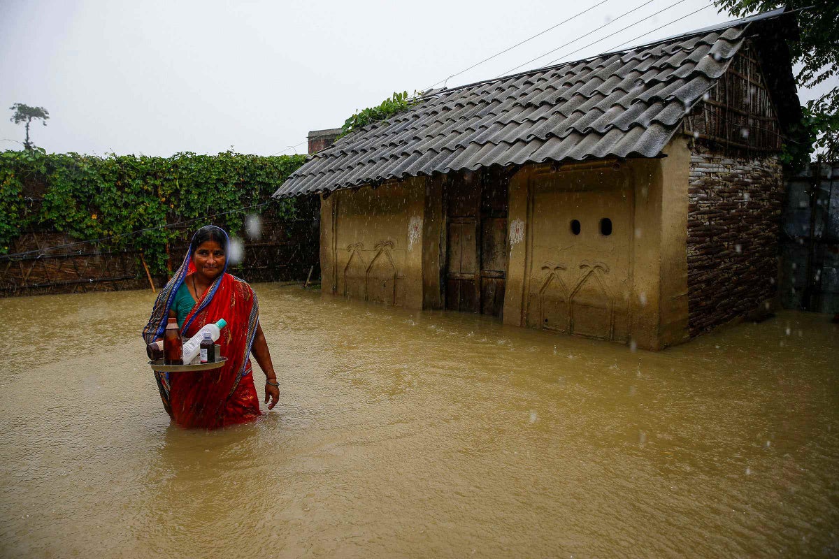 A woman stands outside her flooded house.