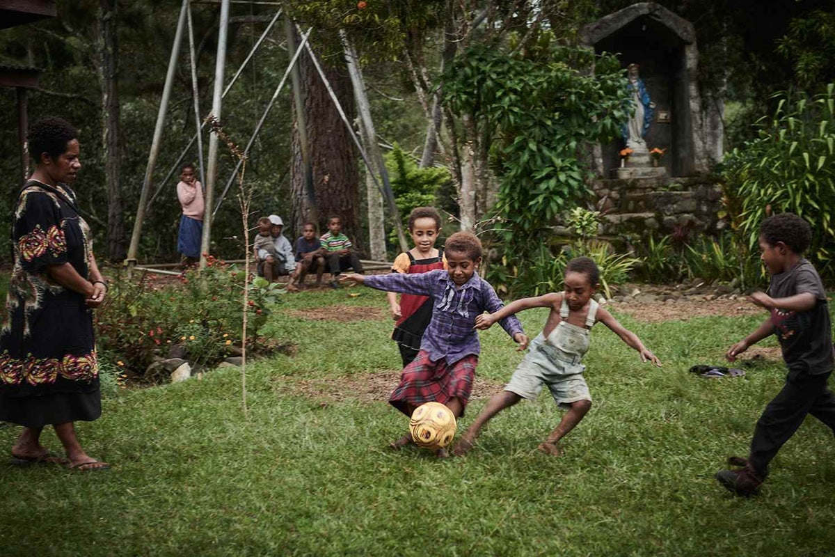 Children from the both tribes in Siure, Chimbu play soccer outside the local church which is on neutral ground.