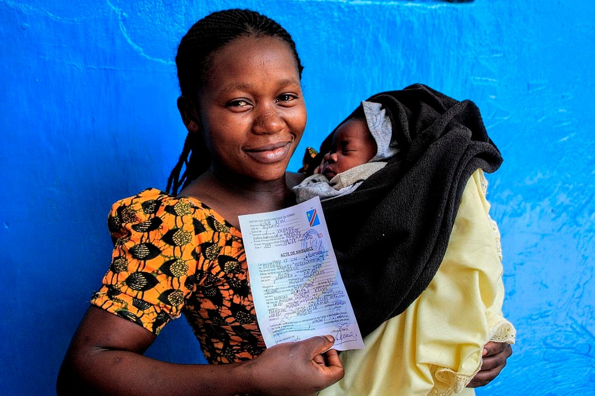 A woman holds her baby and her baby's birth certificate. 
