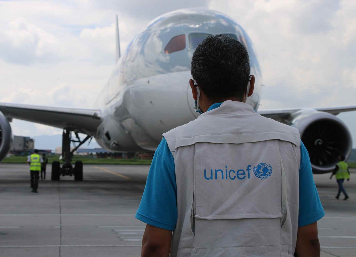 Man standing in front of aircraft, with UNICEF vest on