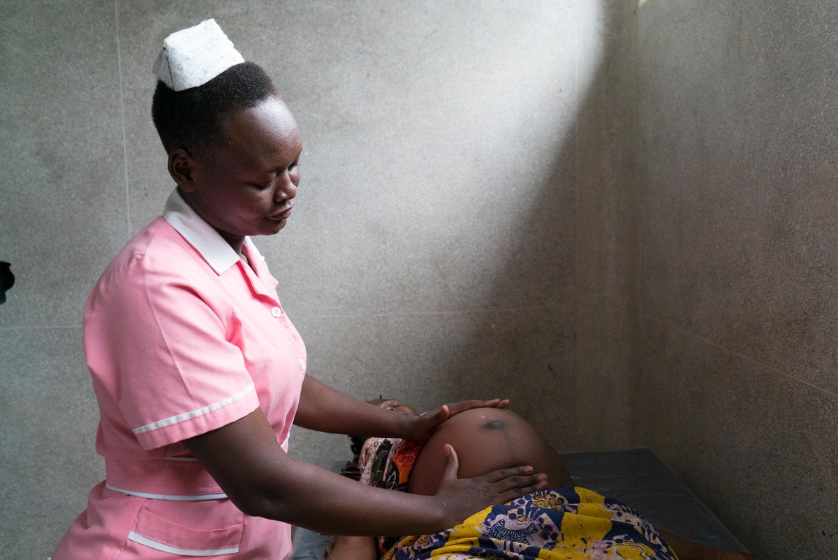 A midwife is performing a check up on a heavily pregnant woman.