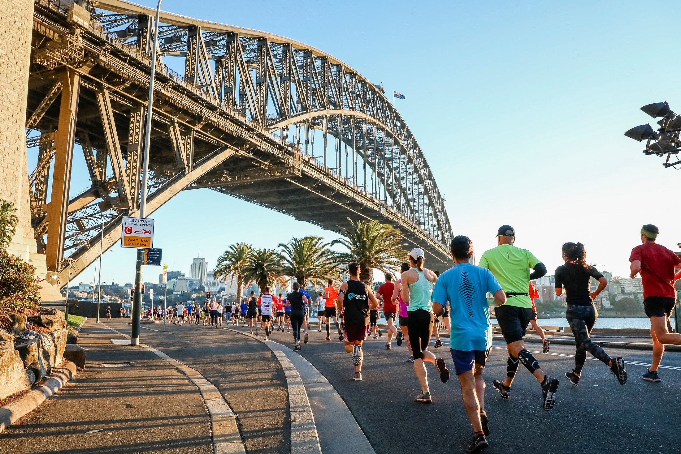 The Sydney Harbour Bridge and people running on the road that goes under it.