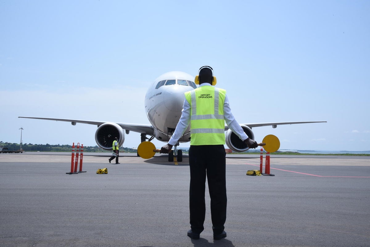 An air traffic controller signalling in front of a plane. 