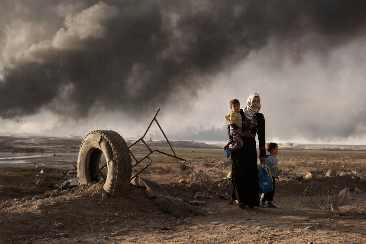 A woman with two young children is in a desolated land.