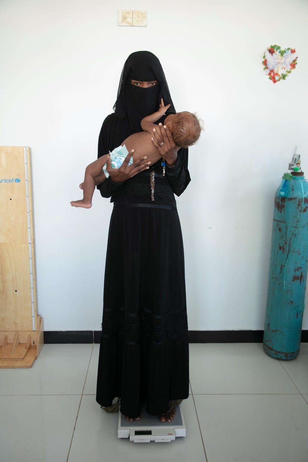 A woman in a burqa holds a baby.