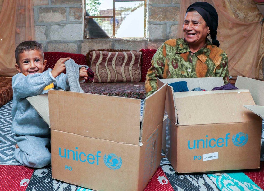 A young Syrian boy and his grandmother unpack a box of supplies from UNICEF